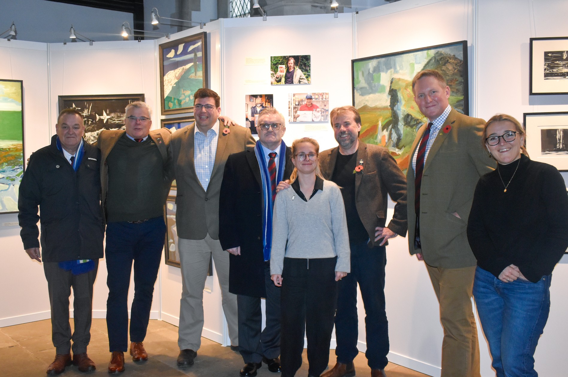 Falklands veterans and waterloo uncovered staff in front of an exhibition of Doug Farthing's artwork.